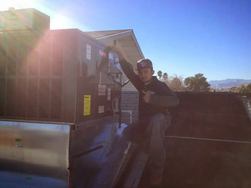 HVAC technician performing AC Tune-Up on a rooftop unit in Macomb